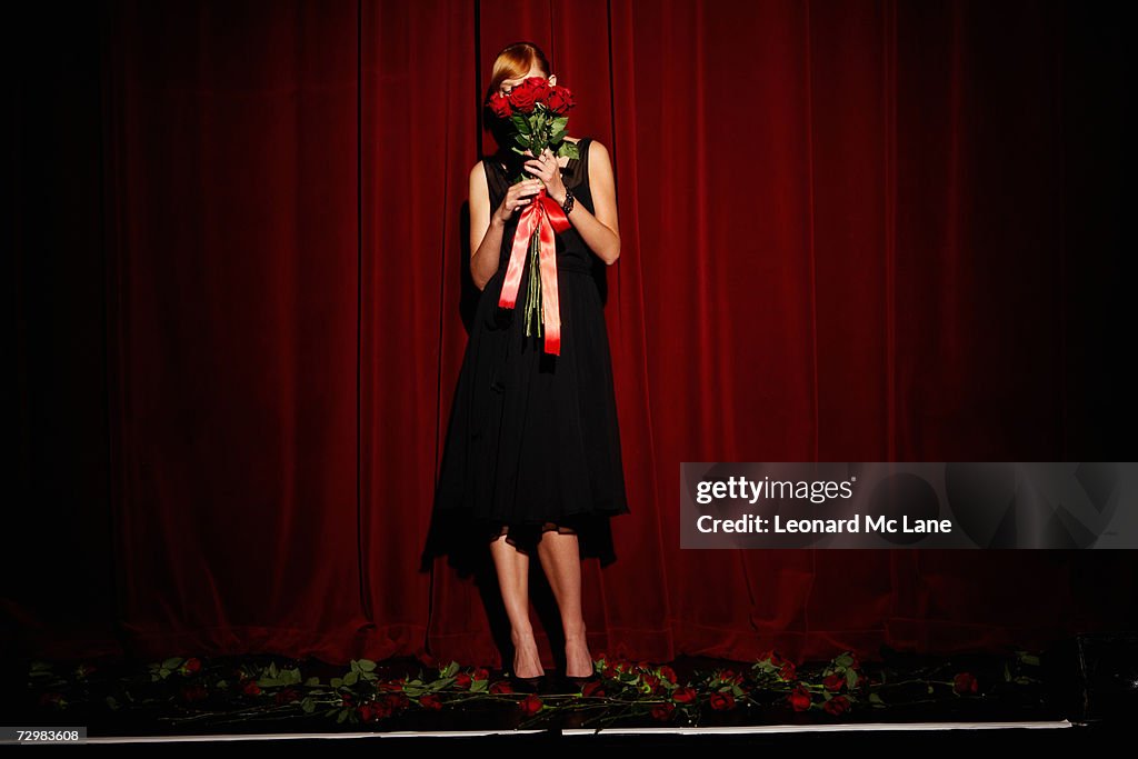 "Young woman on stage holding red roses, low section"