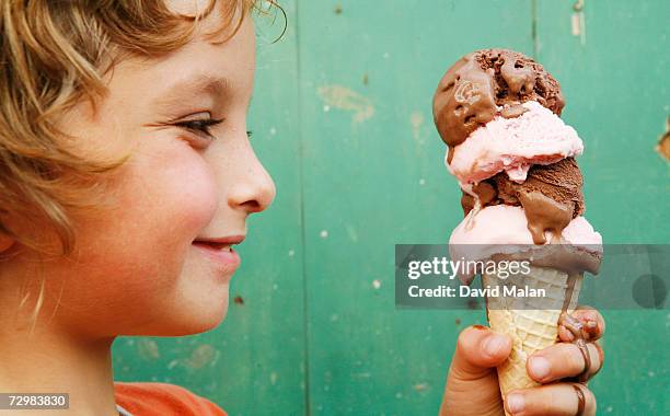 close up of boy (6-7) holding ice cream cone, side view - speiseeis stock-fotos und bilder