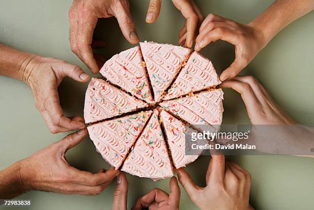 group of eight people reaching for slice of cake, close-up, overhead view - hands share stockfoto's en -beelden