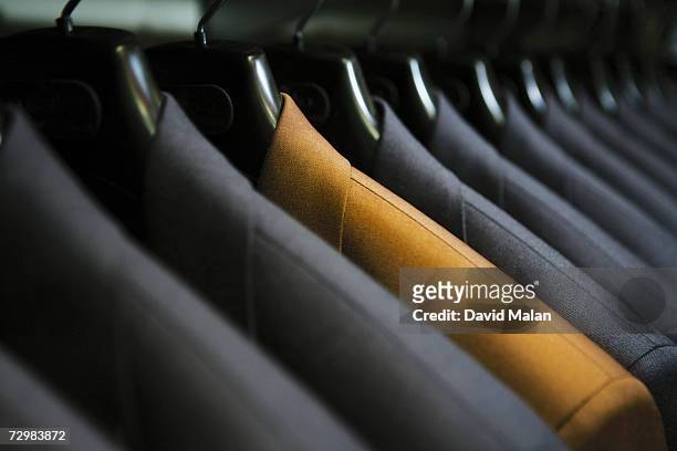 row of hanging suits in wardrobe - individuality foto e immagini stock