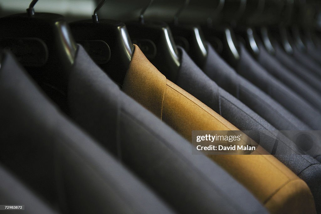 Row of hanging suits in wardrobe