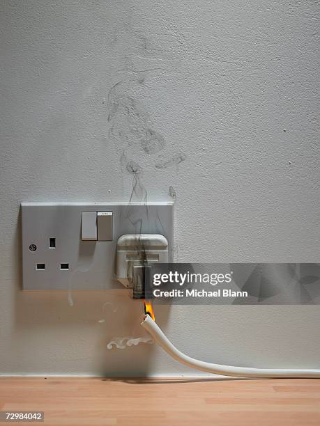 electric plug in wall outlet with smoke and flame - homme fier stock pictures, royalty-free photos & images