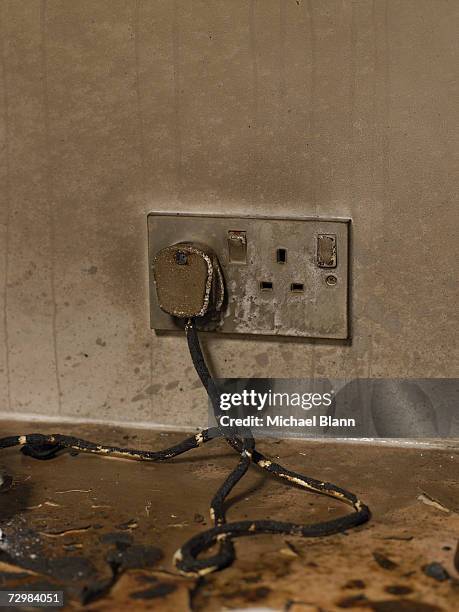 dirty electric plug with frayed cable in dirty wall outlet - frayed stock pictures, royalty-free photos & images