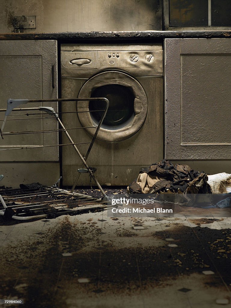 Fire damaged kitchen with washing machine and upturned clothes horse