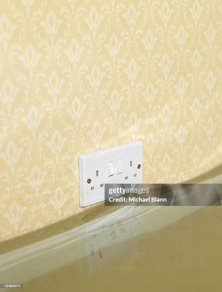 Electric wall outlet reflected in water in flooded living room