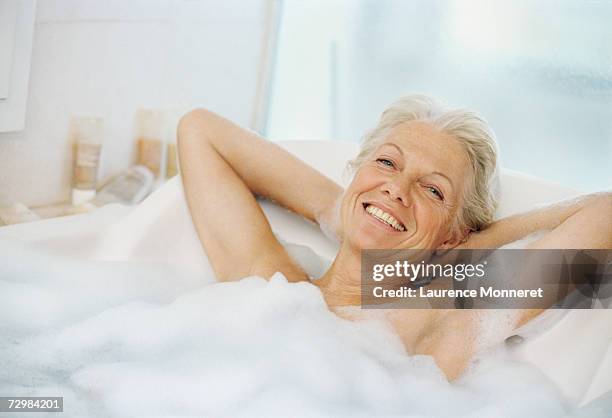 senior woman relaxing in bath, portrait - woman bath bubbles stock-fotos und bilder