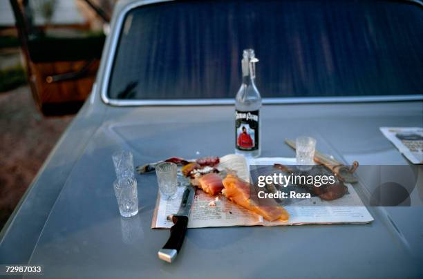 Snack on the road is shown, by the Volga riverside October 1997 in Russian Federation. Sturgeon meat and Stepan Razin vodka sit ready on the car...