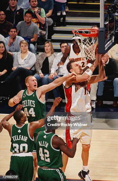 Andris Biedrins of the Golden State Warriors takes the ball to the basket against Brian Scalabrine, Sebastian Telfair and Tony Allen of the Boston...