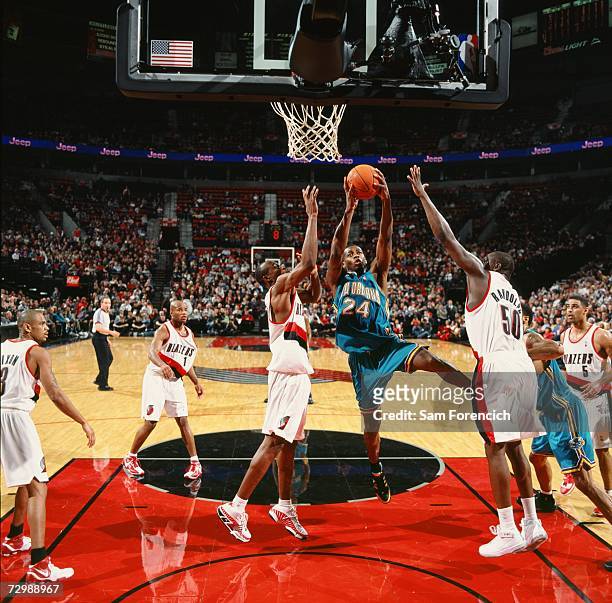 Desmond Mason of the New Orleans/Oklahoma City Hornets takes the ball to the basket against Travis Outlaw and Zach Randolph of the Portland Trail...