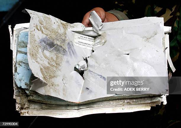 An Indonesian marine soldier displays one of the debris of the missing Adam Air plane as searches goes on in Barru, 13 January 2007. Part of the...