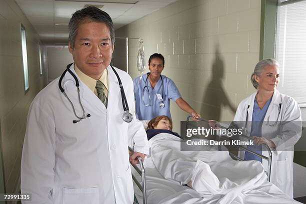 Doctors And Nurse With Patient On Gurney In Hospital Corridor Male Doctor Smiling High-Res Stock Photo