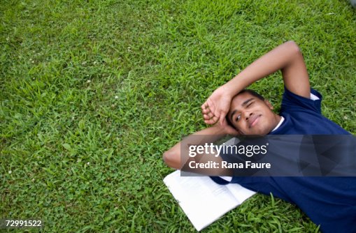 Teenage boy (16-17) lying on grass, elevated view Teenage boy (16-17) lying on grass, elevated view