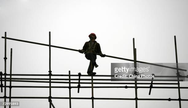 Migrant worker erects scaffoldings at a construction site on January 13, 2007 in Chongqing Municipality, China. Economists from Chinese Academy of...