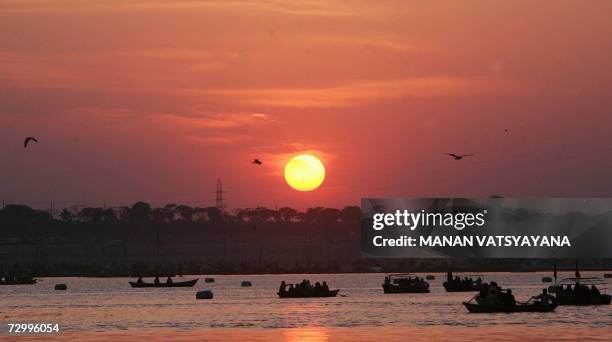 The sun sets as boats carry Hindu devotees to Sangam, the confluence of the Ganges, Yamuna and Saraswati rivers in Allahabad, 14 January 2007, during...