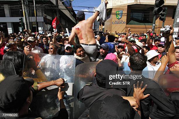 Guatemala City, GUATEMALA: Un miembro de un grupo social con heridas en su espalda es llevado en andas durante un enfrentamiento con la Policia...