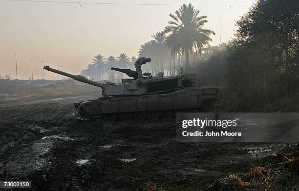 Army tank crew member looks into the hatch of his M1A1 Abrams in the mud January 15, 2007 in Ramadi in Iraq's Anbar province. U.S. Forces and...