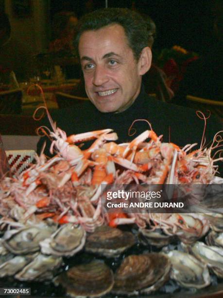 Nicolas Sarkozy, French Interior Minister and freshly anointed as centre-right candidate in April's presidential, smiles next to a seafood platter...