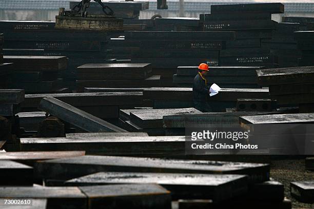 Worker walks past steel ingots at a Shanghai Baosteel Group factory January 15, 2007 in Shanghai, China. According to state media, Baosteel is...