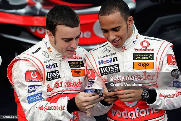 Fernando Alonso of Spain and Lewis Hamilton of Great Britain use their mobile phones during The Vodafone McLaren Mercedes Formula One Grand Prix team...