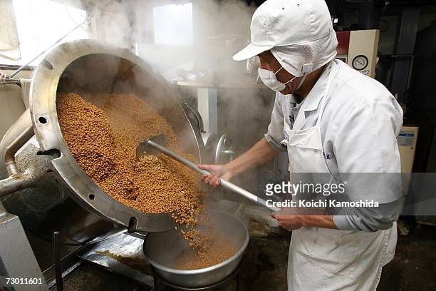 Factory worker empties boiled soybeans on the food production line processing natto at the Daruma Shokuhin Co factory on January 16, 2007 in Mito,...