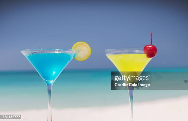 blue and yellow cocktails in martini glasses on tropical beach - blue martini glasses stock-fotos und bilder
