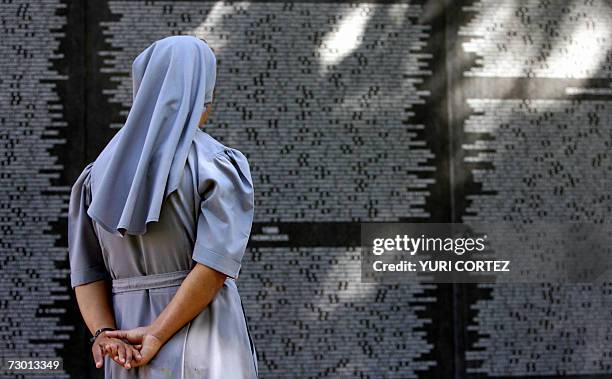 San Salvador, EL SALVADOR: Una religiosa observa un mural con los nombres de miles de victimas del pasado conflicto armado asesinados o desaparecidos...