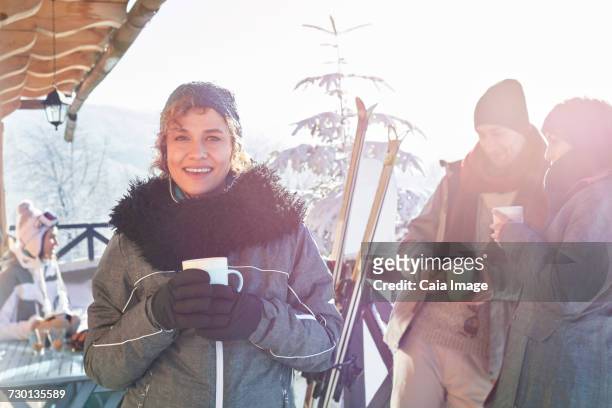 portrait smiling female skier drinking coffee on cabin deck with friends apres-ski - hot toddy stockfoto's en -beelden