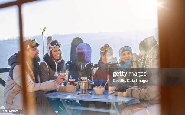 snowboarder friends drinking and eating at balcony table apres-ski - hot toddy stock pictures, royalty-free photos & images