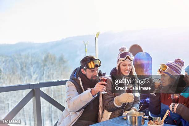 snowboarder and skier friends drinking cocktails on balcony apres-ski - apres ski stock pictures, royalty-free photos & images