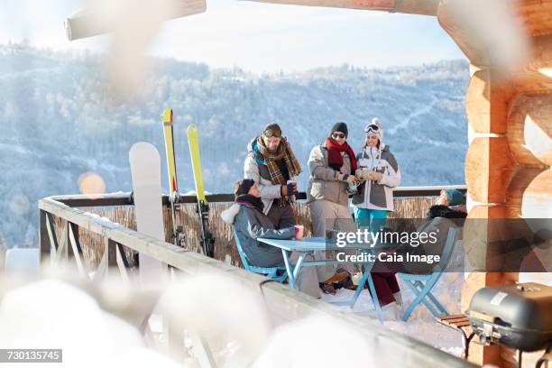 skier and snowboarder couples hanging out on sunny cabin balcony apres-ski - hot toddy stock pictures, royalty-free photos & images