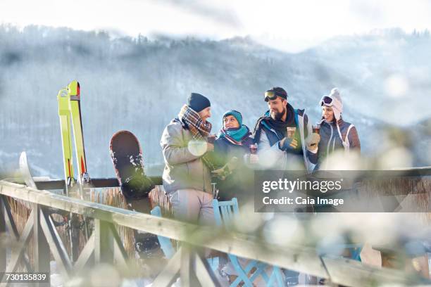 skier friends talking and drinking cocktails on sunny balcony apres-ski - hot toddy stockfoto's en -beelden