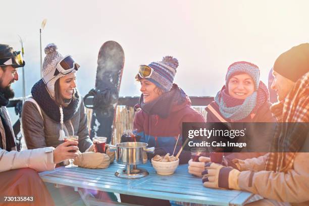 snowboarder friends drinking cocktails on sunny balcony apres-ski - caiaimage stock-fotos und bilder