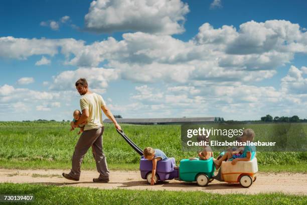 father carrying baby son while pulling four children in a wagon - large family bildbanksfoton och bilder