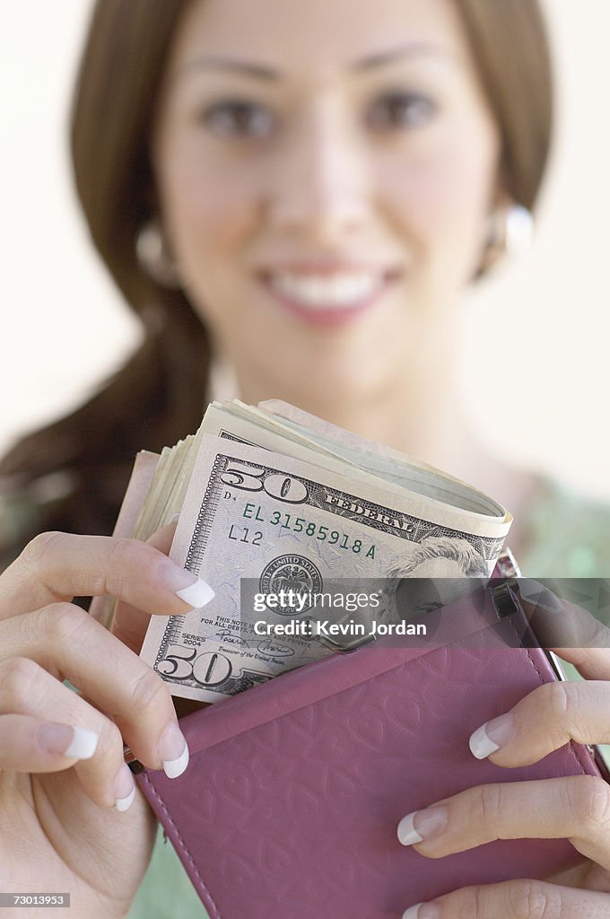 Young woman holding banknotes, smiling, close-up, portrait