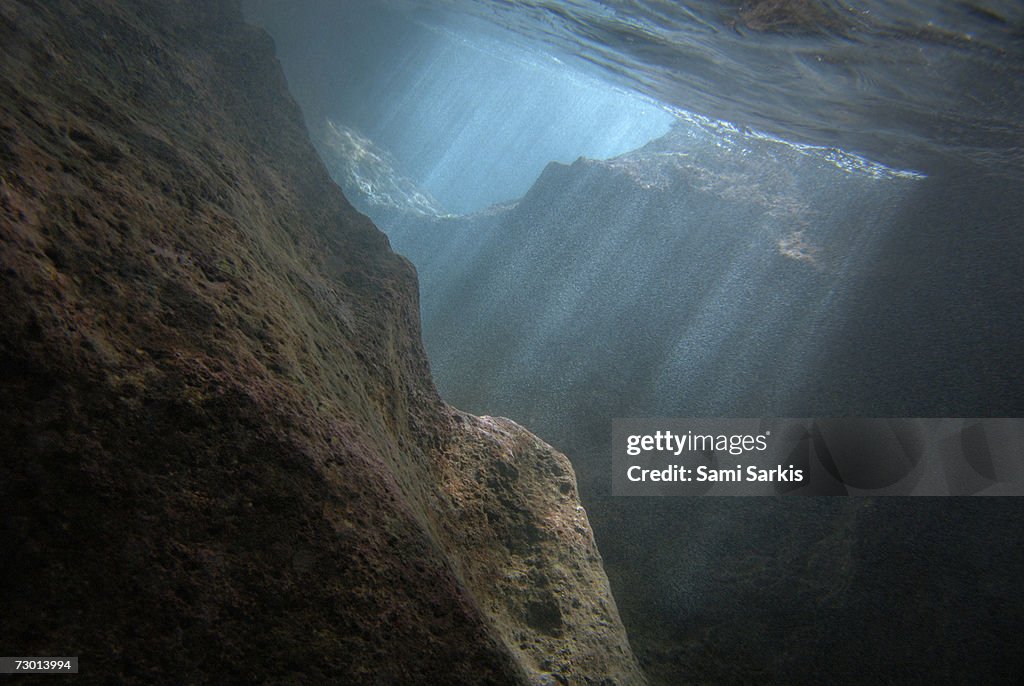 Sunrays penetrating underwater cave near surface, underwater view