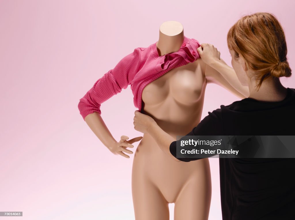 Woman dressing mannequin, rear view