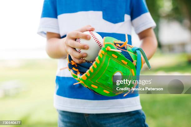 mid section of boy (6-7) holding baseball ball - baseball glove stock pictures, royalty-free photos & images