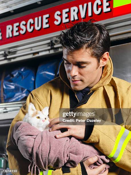 fireman holding rescued cat, close-up - brandweeruniform stockfoto's en -beelden