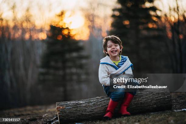 boy sitting on a log laughing - day 4 fotografías e imágenes de stock