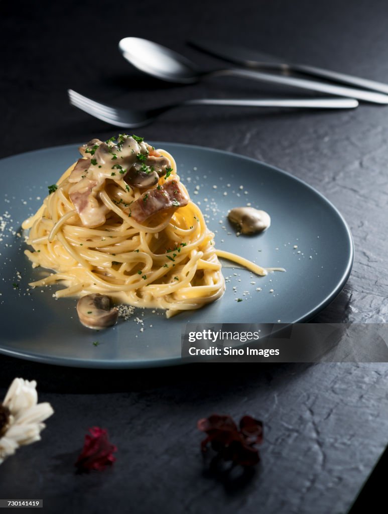 Table arranged with plate of spaghetti, cutlery and bowl with salad