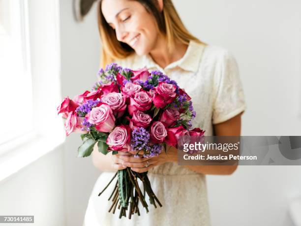 woman holding bouquet of roses - bouquet stockfoto's en -beelden