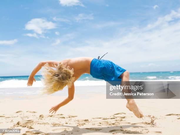 boy (8-9) backfilling on beach - pacific rim gymnastics stock pictures, royalty-free photos & images