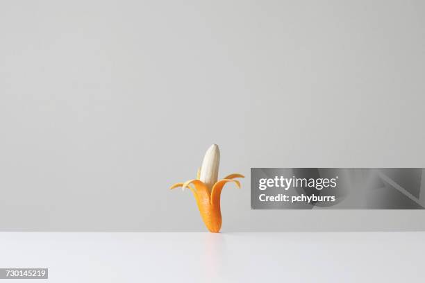 conceptual banana in an orange skin - banana skin stock-fotos und bilder