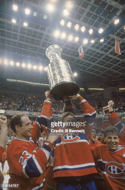Canadian professional ice hockey players Bob Gainey and Larry Robinson of the Montreal Canadiens and Swedish teammate Mats Naslund lift the Stanley...