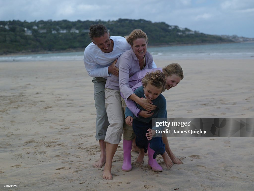 Family with two children (7-10) hugging on beach