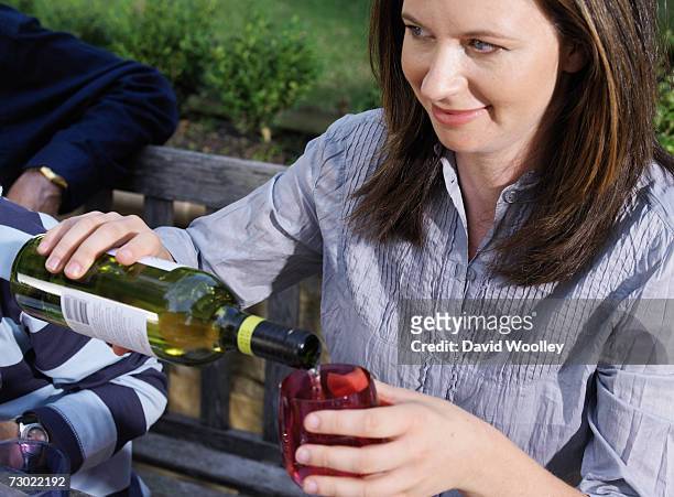 woman pouring white wine from bottle into glass in garden - einzelne frau über 30 stock-fotos und bilder