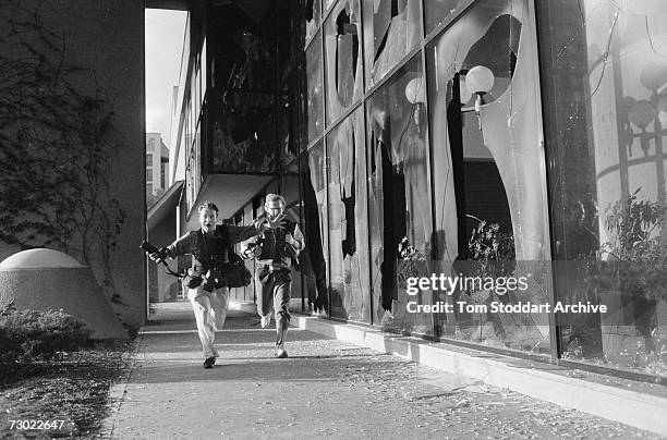 Photographers Paul Lowe and David Turnley run for cover beside the Holiday Inn hotel which was home to the media during the war. During the 47 months...