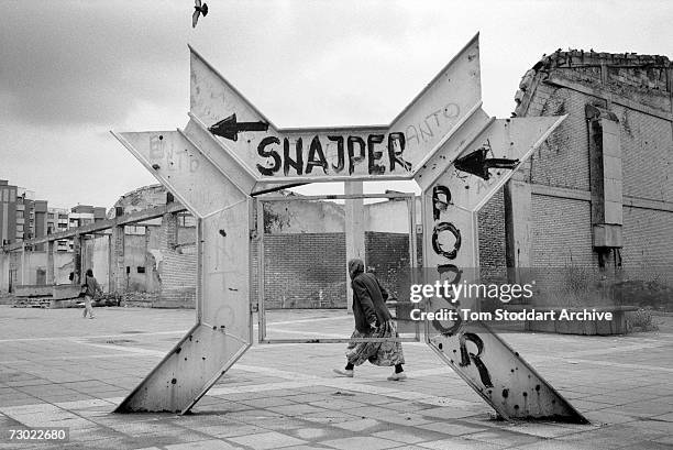 Muslim woman hurries past graffiti warning of snipers in a dangerous part of Sniper Alley. During the 47 months between the spring of 1992 and...