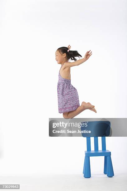 girl (5-7) jumping off chair, side view - innocence stock pictures, royalty-free photos & images