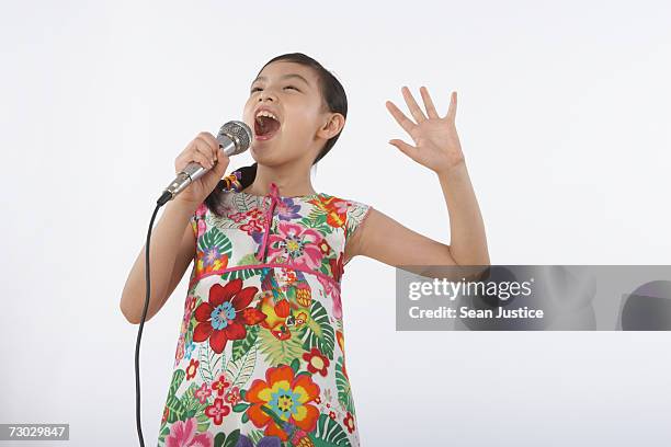 girl (6-8) singing into microphone - singing for kids stock pictures, royalty-free photos & images